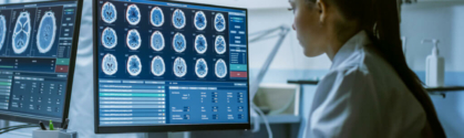 The benefits of AI in healthcare hero shows a female doctor looking at a computer screen. On the screen are a series of brain scans.